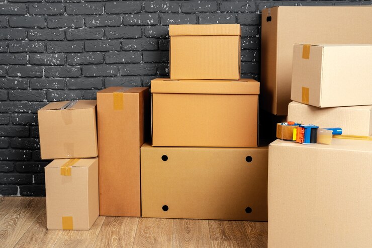 stack cardboard boxes empty room against black brick wall 93675 116041 - KHILJEE PACKAGING